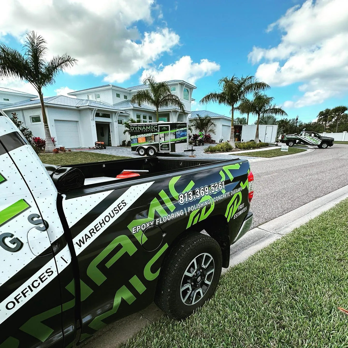 Dynamic Floor Coatings wrapped trucks and trailer outside a residential job site in Tampa